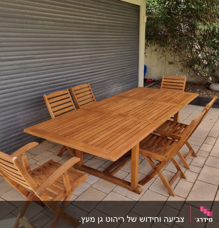 שולחן עץ עם כיסאות בגינה על מרצפות